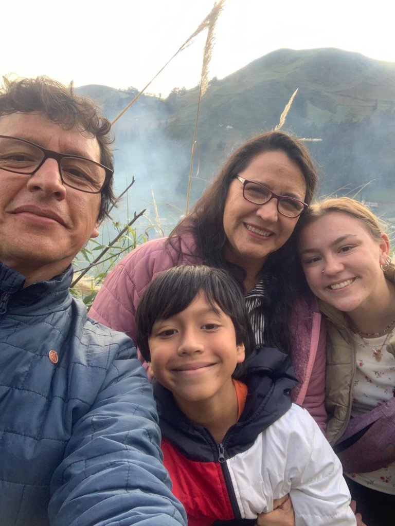 A selfie of a student with a host family in a mountain setting.
