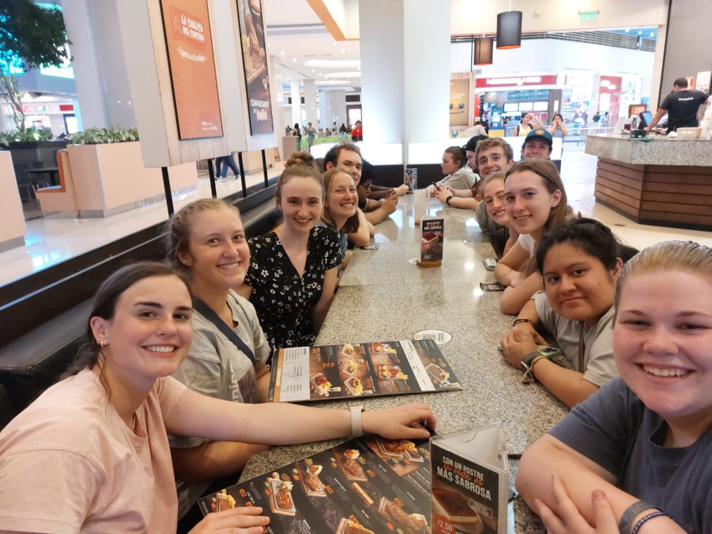 Students taking a group selfie at a mall food court.
