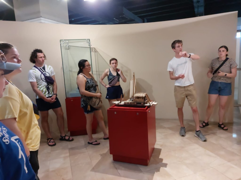 Students gathered around a display case in a museum room.