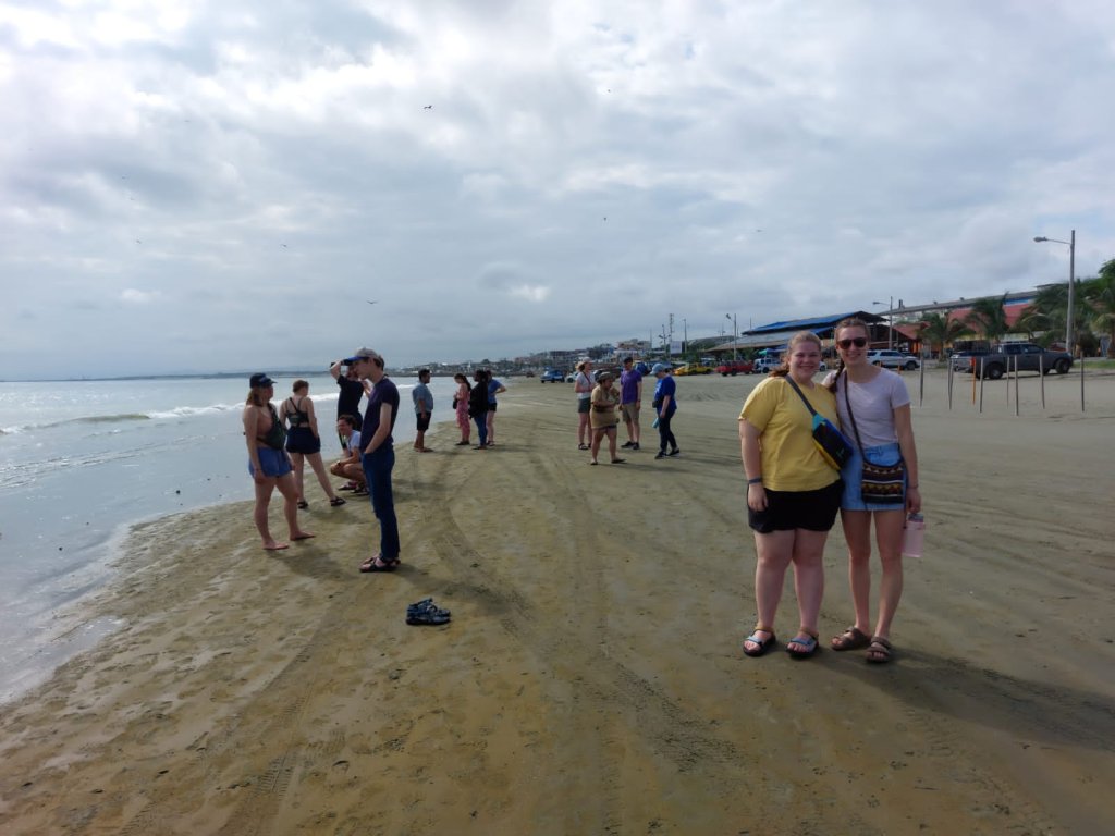 A group of students standing together on the wet sand of a beach.