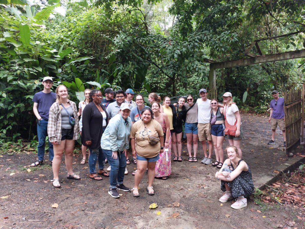 A group of students posing together on a forest trail.
