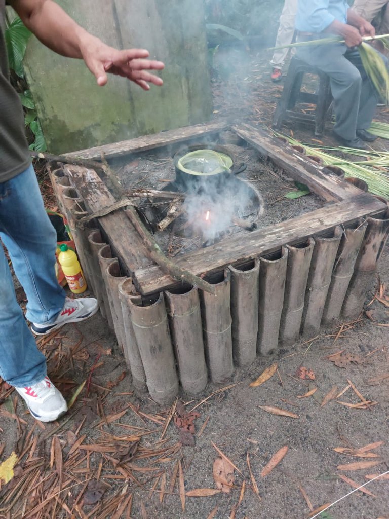 A metal pot boiling over a wood fire pit.

