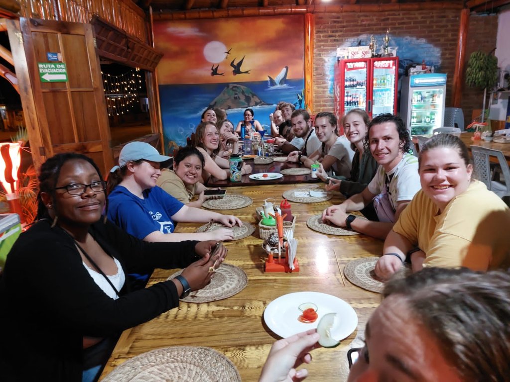 A group of students sharing a meal around a table at a restaurant.