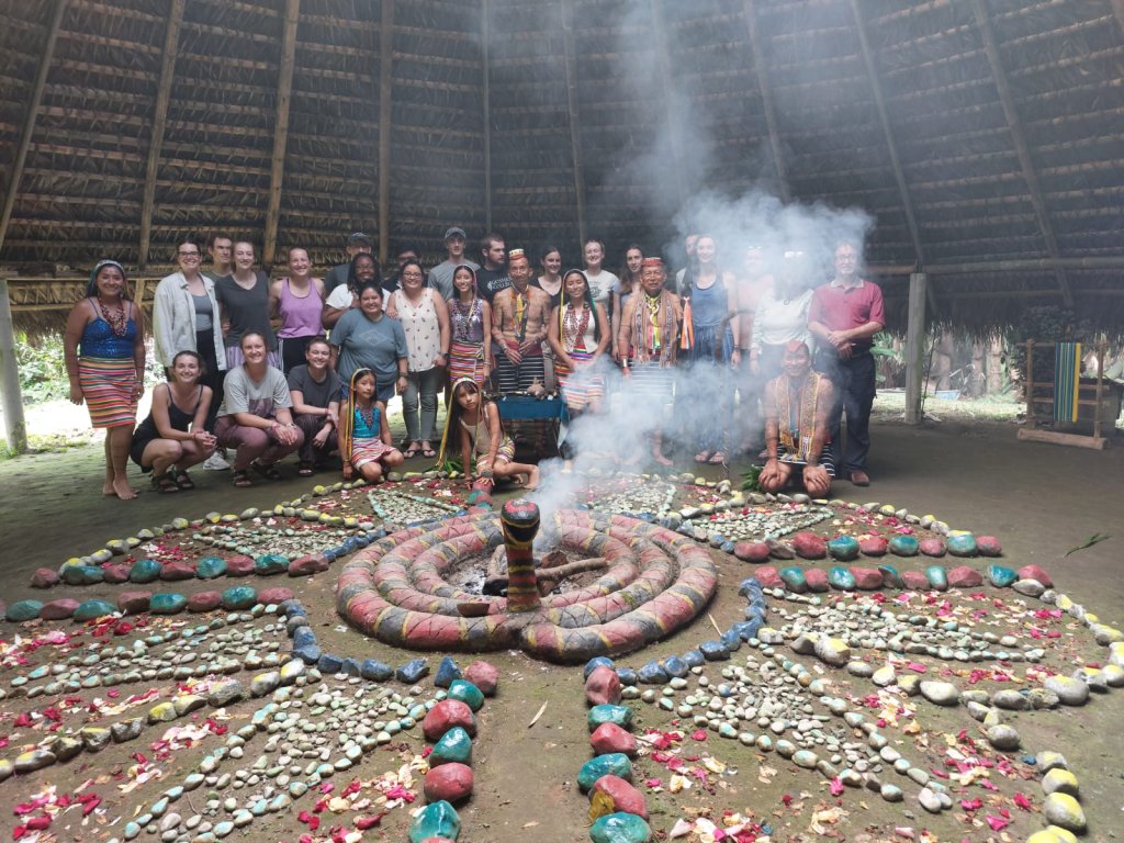 A group photo with performers around a decorated ceremonial mandala.
