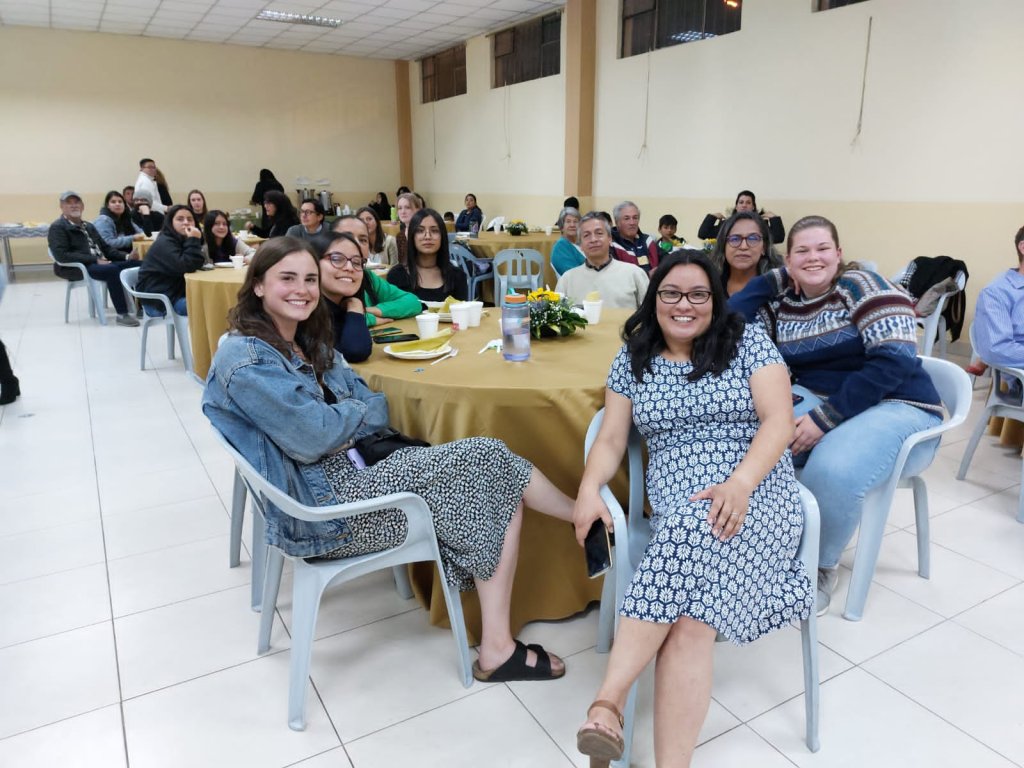 Two women seated at a table smiling at an event.
