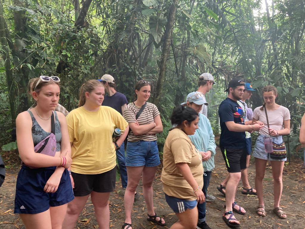 Students gathered listening to a guide in the forest.