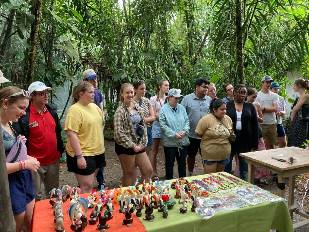 A group of students at a craft table with painted figurines.
