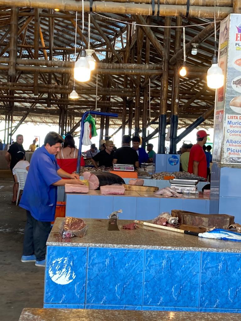 An indoor fish market with vendors and stalls beneath a roof.
