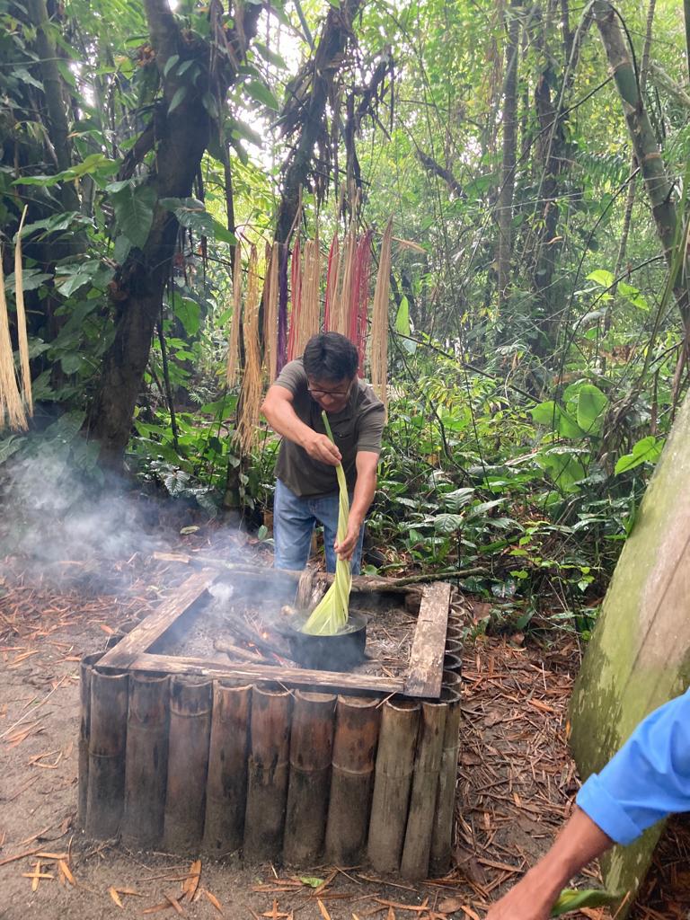A person stirring a steaming vat during the straw-processing demonstration.
