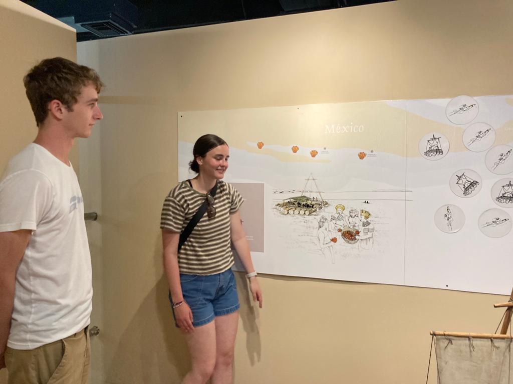 Two students looking at illustrated exhibit panels on a wall.