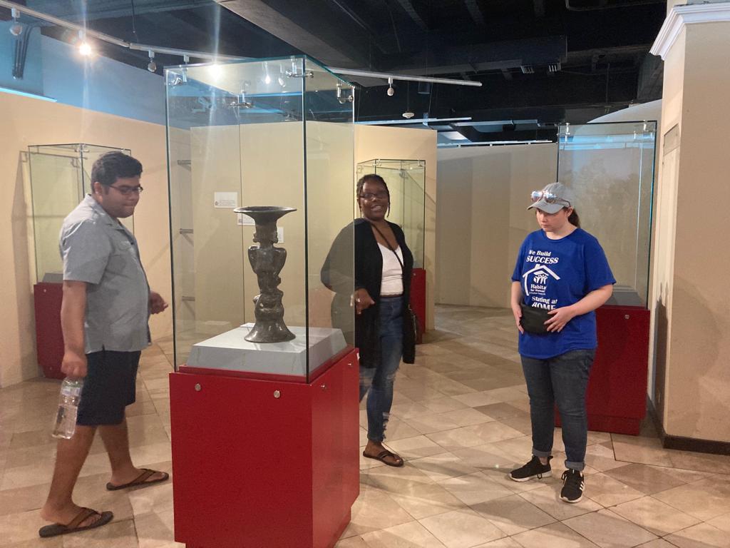 Visitors examining an artifact inside a glass display case.