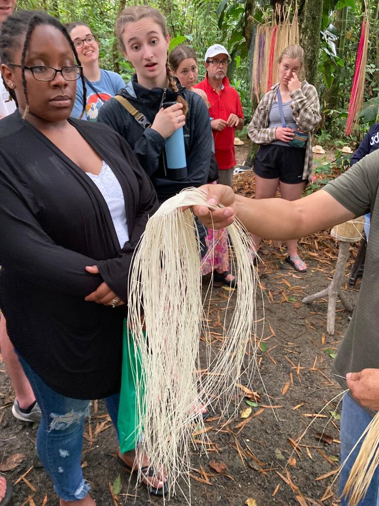 A person holding out processed straw fibers to the group.
