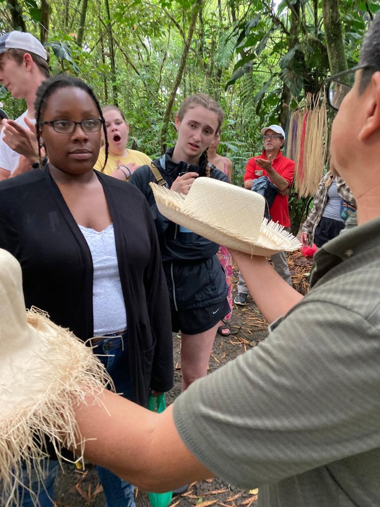 A demonstrator showing a finished Panama hat to students.
