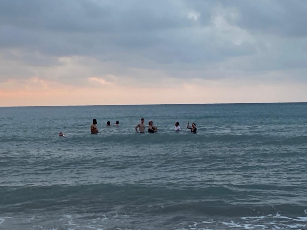 A group of people swimming in the ocean at dusk.