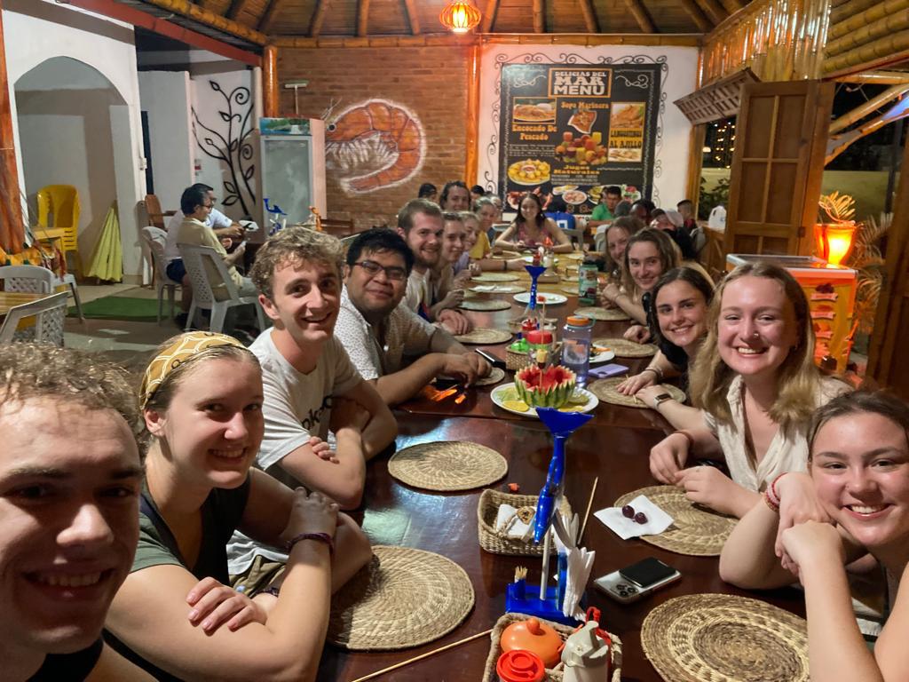 Students posing together at a dinner table in a rustic restaurant.