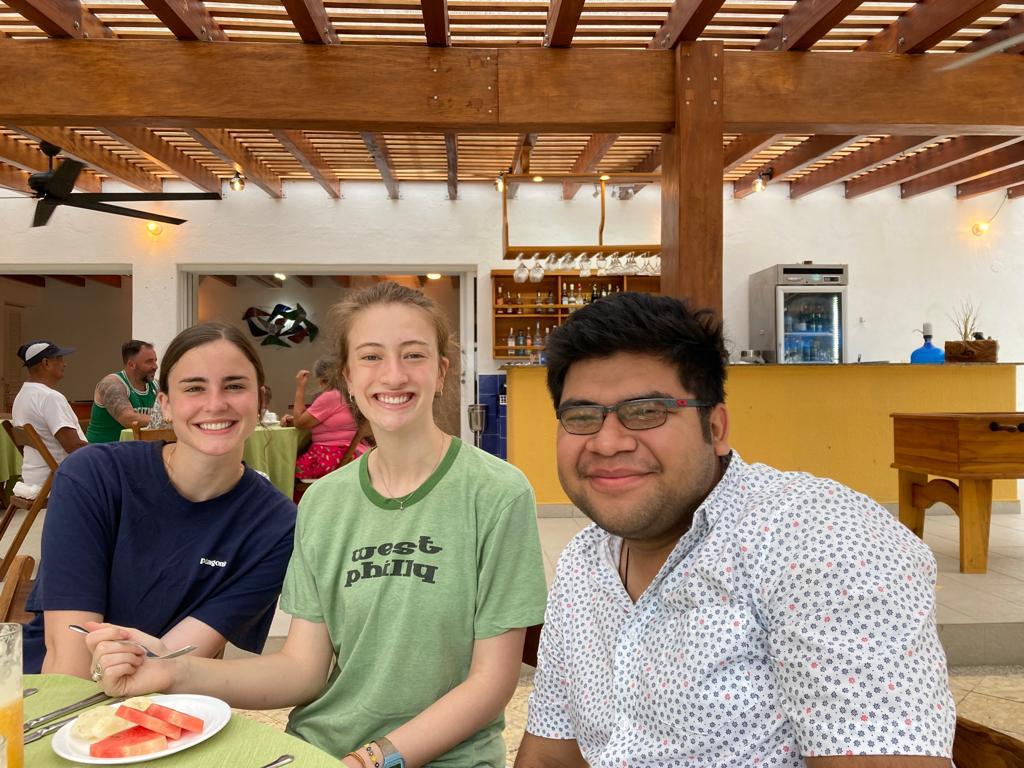 Three students posing at a table with slices of watermelon.