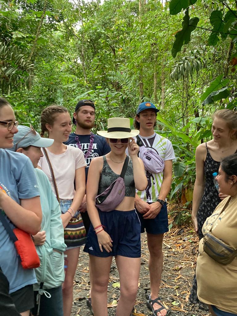A group of students trying on hats along a forest trail.
