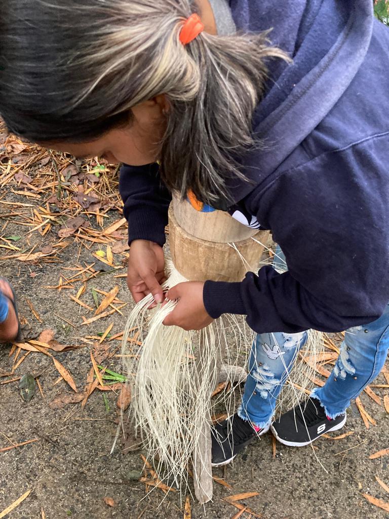 A person holding a bundle of processed straw fibers.
