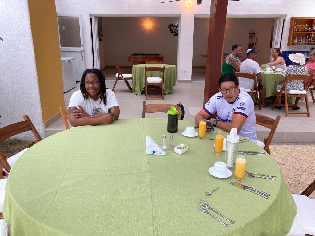 People seated around a green-clothed table on a patio.