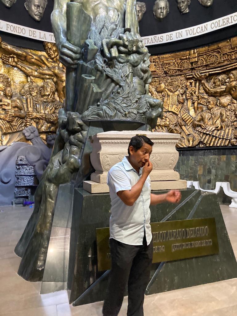 A person standing before an ornate golden sculptural monument.
