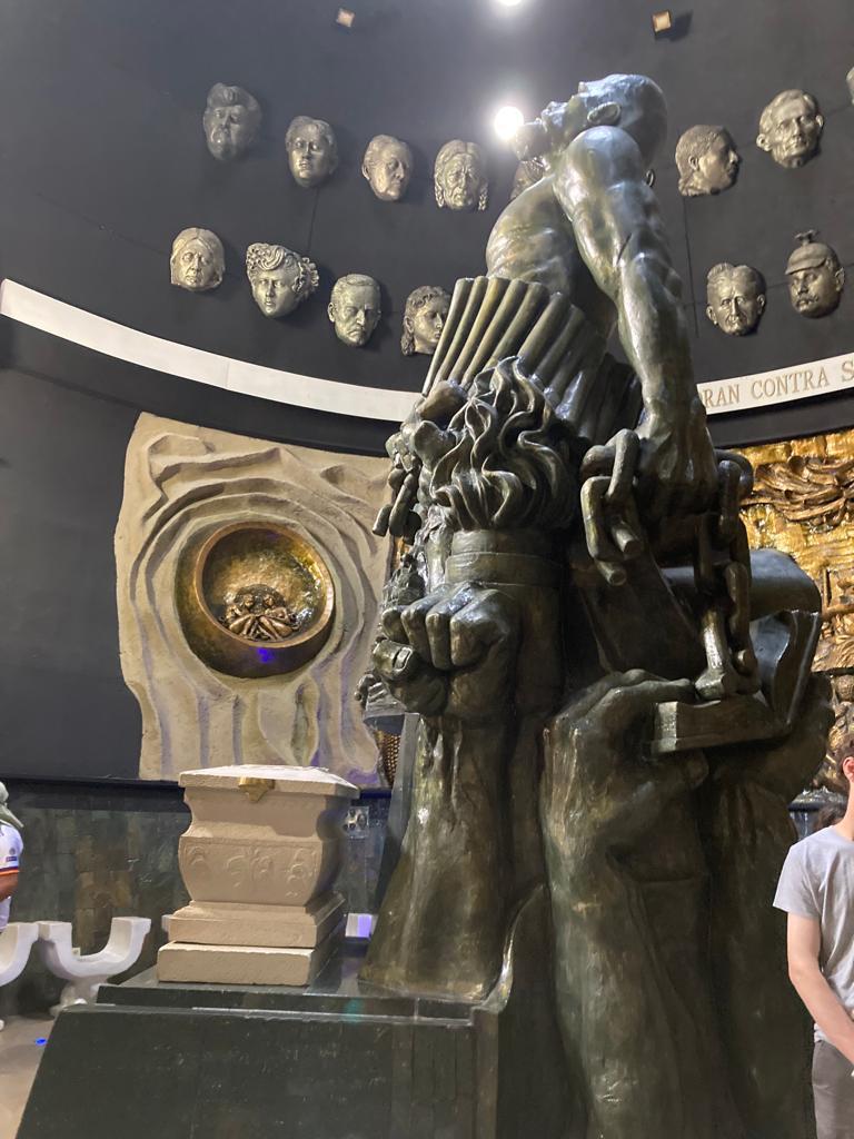 A tall bronze statue on a pedestal in an exhibition hall.
