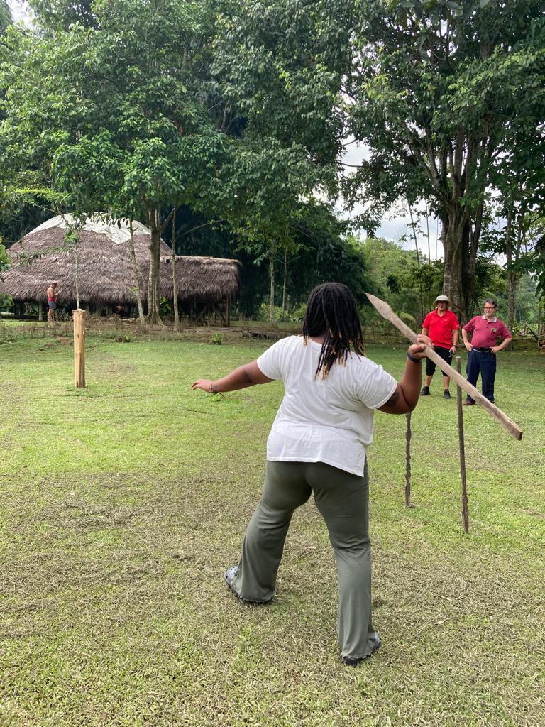 A student throwing a spear during a demonstration on the lawn.
