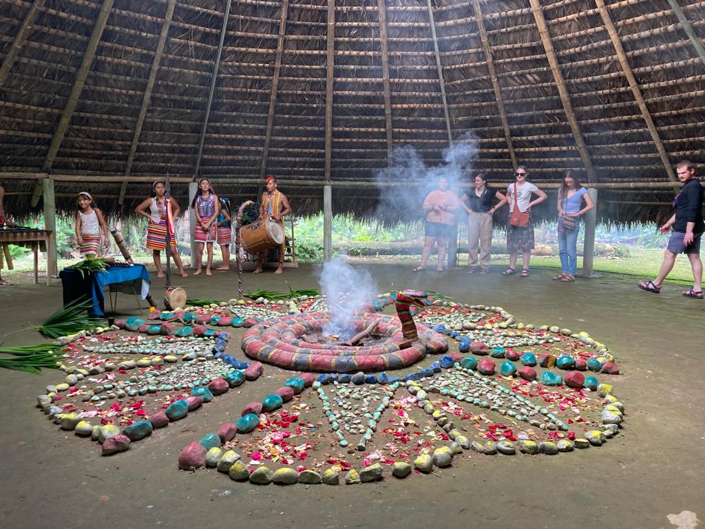 A circular decorated altar of fruits and stones with rising smoke.
