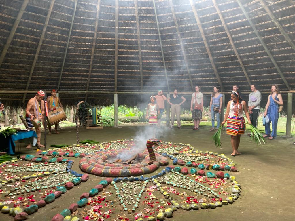 Participants observing a smoking ceremonial display in the hut.

