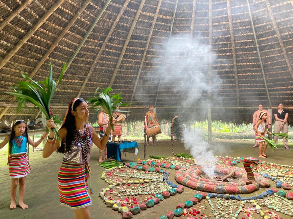 A woman holding leaves during a ritual beside the smoking altar.
