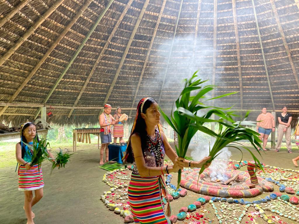 A woman performing a ceremony with a plant near the central altar.
