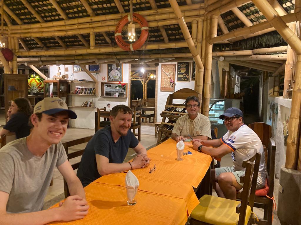 Three people at an orange-clothed table in a wooden restaurant.

