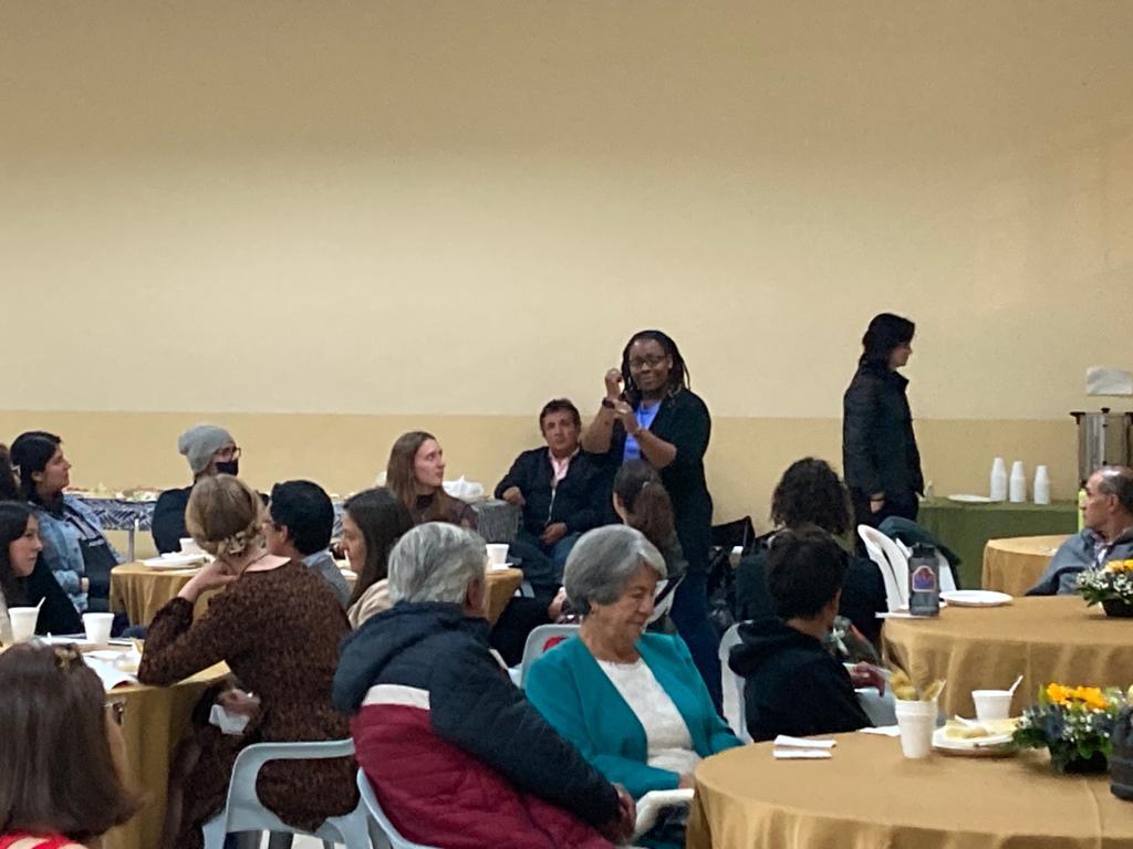 People seated and standing at a community gathering.
