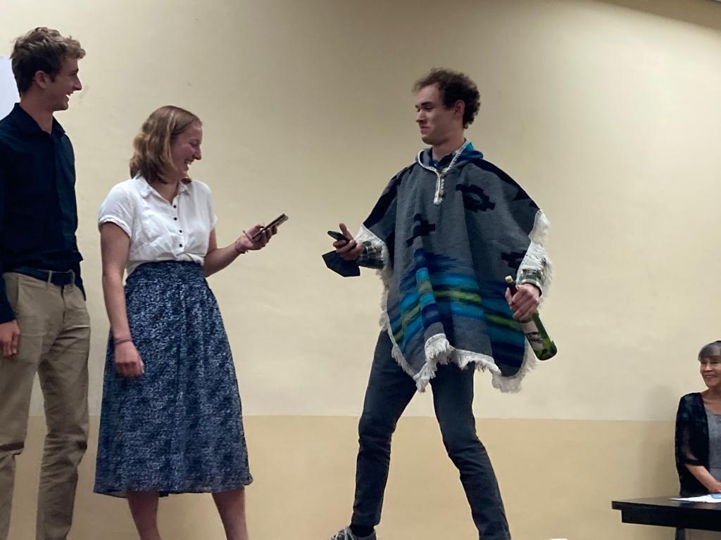 Students performing a skit, one wearing a poncho.

