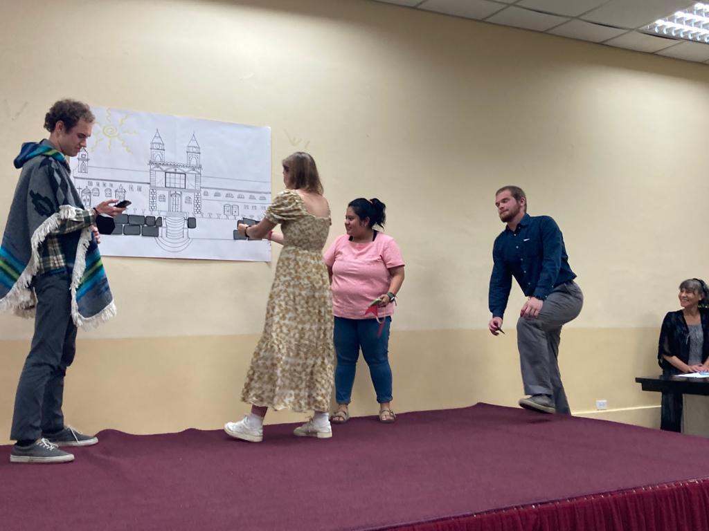 Students acting out a scene on stage in costume.
