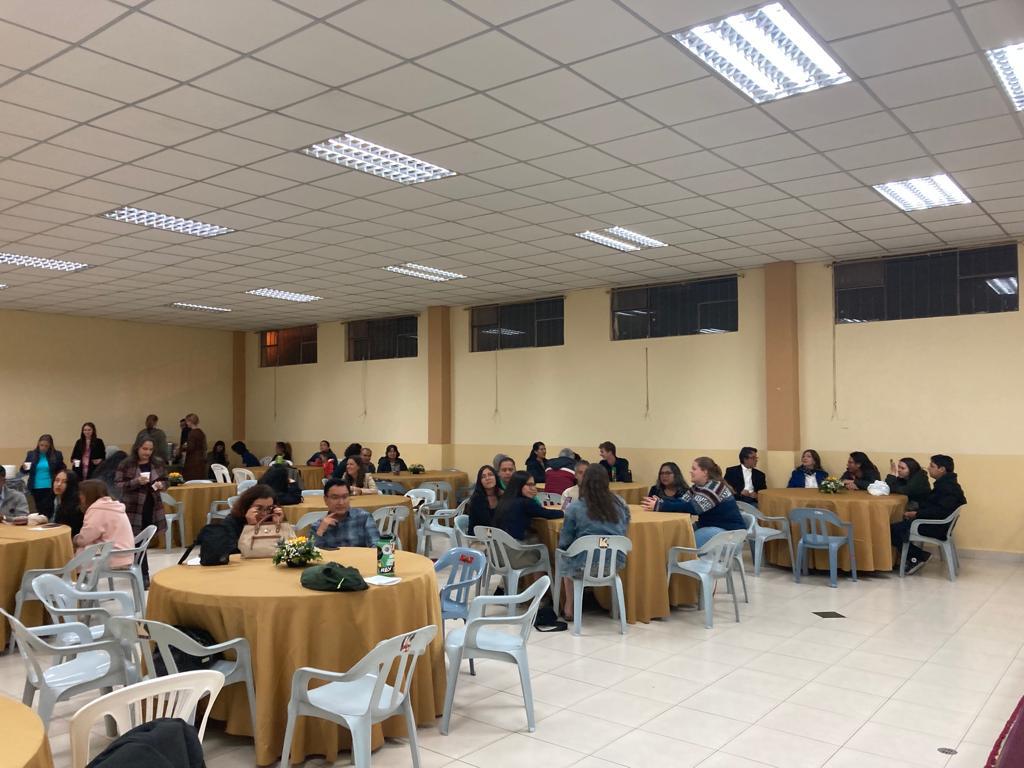 A room full of people seated at round tables for an event.
