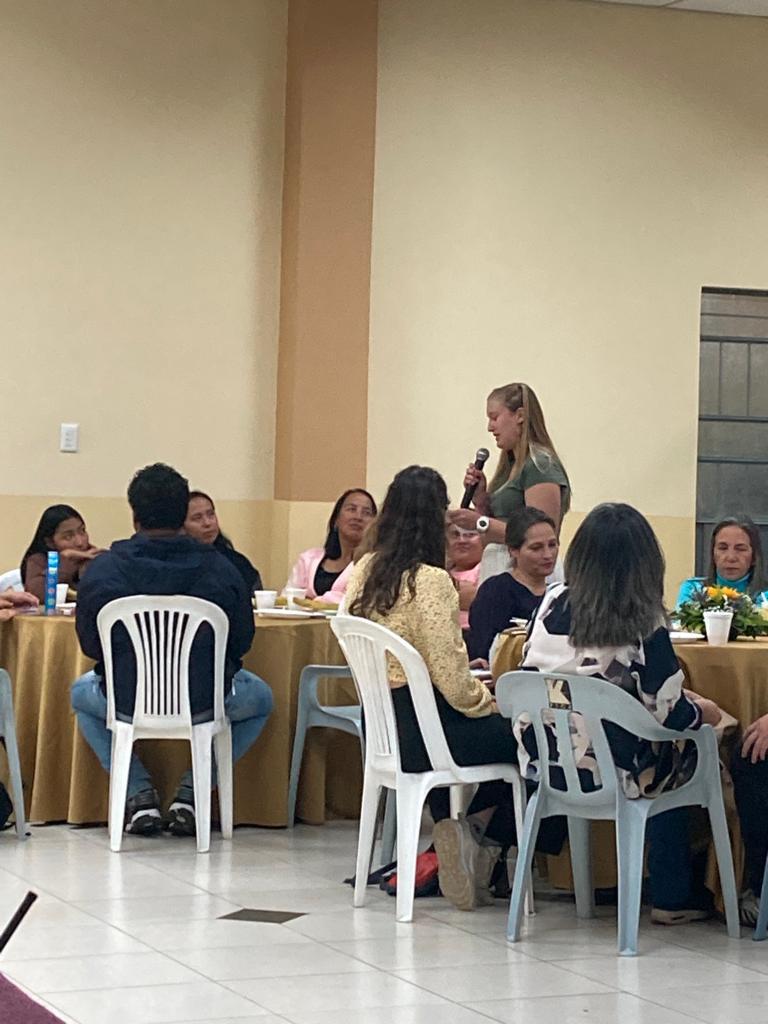 Attendees seated around a table at an indoor event.
