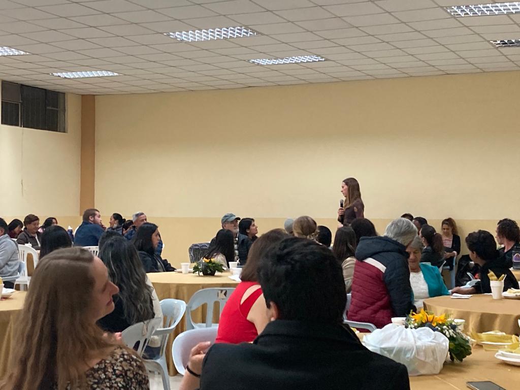 Attendees gathered at tables listening at an event.
