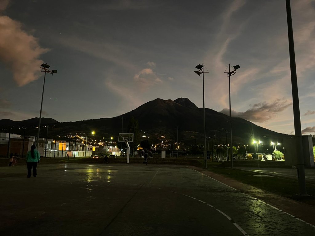 A dusk view of a town square with a mountain silhouette behind.

