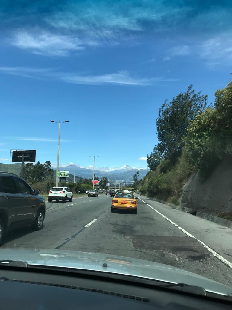 A view of the road and mountains through a car windshield.
